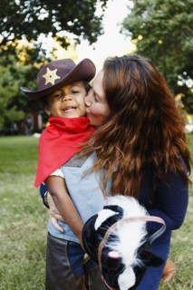 Mother kissing son dressed as cowboy for Halloween