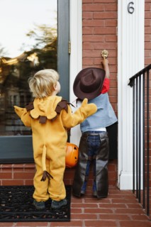 Boys in costumes trick or treating together on Halloween