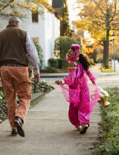 African American girl trick-or-treating with father on Halloween