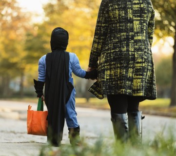 African American boy trick-or-treating with mother on Halloween