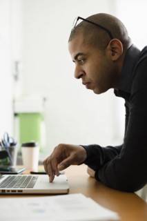 Mixed race businessman working on laptop at desk