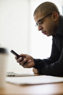 Mixed race businessman using cell phone at desk