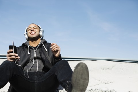 Mixed race man listening to headphones on beach