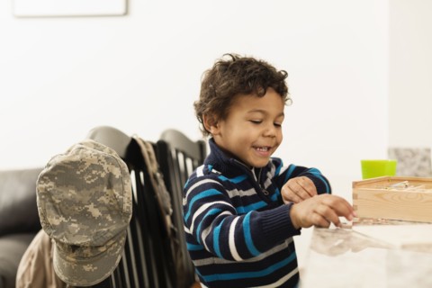 Mixed race boy playing at counter near camouflage cap