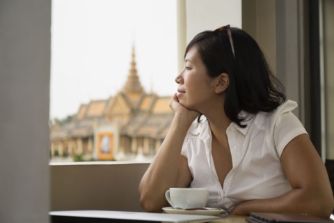 Asian woman looking out cafe window