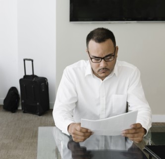 Hispanic businessman reading paperwork in office
