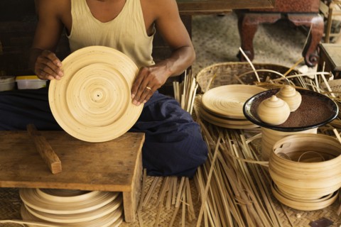 Asian artisan weaving traditional baskets in workshop
