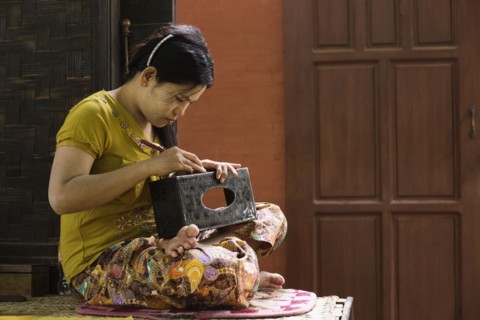 Asian artisan carving traditional design in workshop
