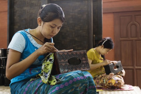 Asian artisans carving traditional design in workshop