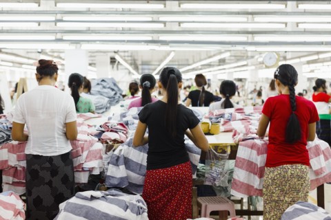 Asian workers sewing clothing in garment factory