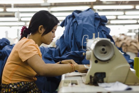 Asian worker sewing clothing in garment factory