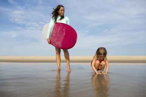 Mother and daughter playing in waves on beach