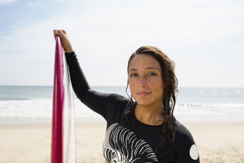 Hispanic surfer holding surfboard on beach