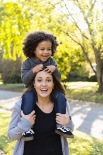 Mother carrying son on shoulders outdoors
