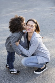 Boy kissing cheek of mother outdoors