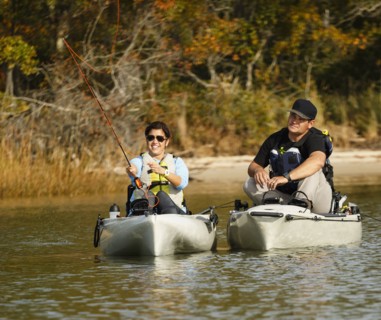 Couple fly fishing in kayaks on river