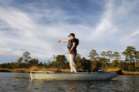 Caucasian man fly fishing in kayak on river