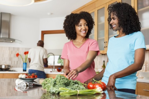 Black women chopping vegetables in kitchen