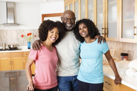 Black family hugging in kitchen