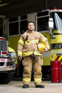 Serious Chinese fireman posing near fire trucks