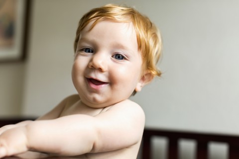 Portrait of smiling Caucasian baby boy standing in crib