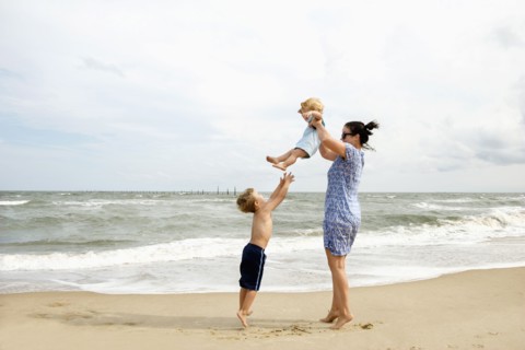 Caucasian mother and sons playing at beach