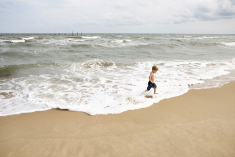 Caucasian boy running in waves at beach