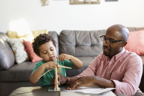 Father and son building model windmill in livingroom