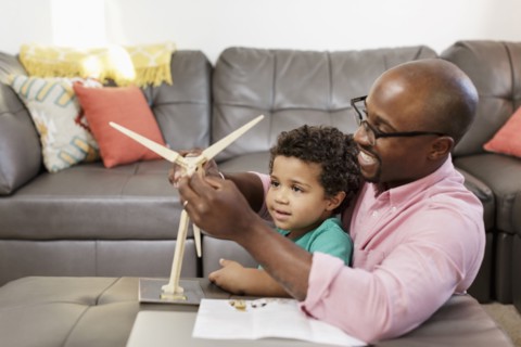 Father and son building model windmill in livingroom