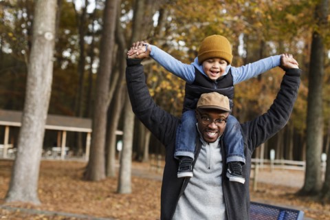 Father carrying son on  shoulders in park
