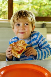 Playful Caucasian boy eating slice of pizza