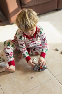 Caucasian boy sitting on floor in pajamas playing with toys
