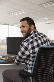 Smiling Mixed Race man using computer in office