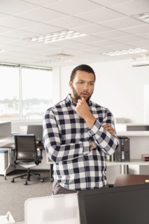 Pensive Mixed Race man standing in office