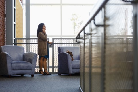 Pacific Islander woman talking on cell phone in lobby