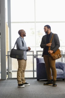 Men carrying briefcases talking in lobby