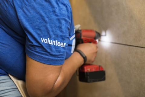 Volunteer black woman drilling wall