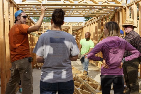 Volunteers talking while building a house