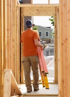 Caucasian man carrying ladder at construction site