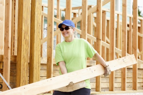 Caucasian woman carrying lumber at construction site