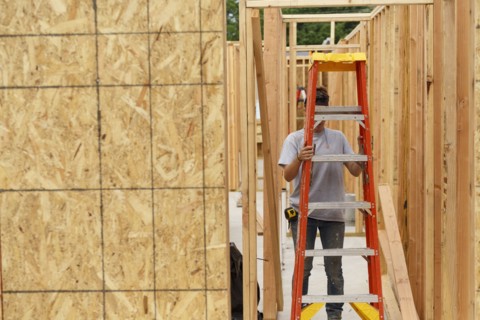 Caucasian woman carrying ladder at construction site