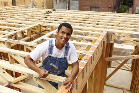 Portrait of mixed race man hammering nail at construction site