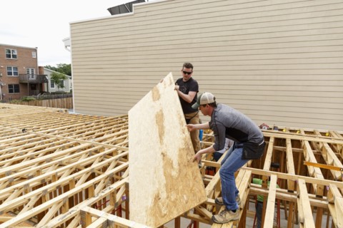 Caucasian men carrying plywood at construction site