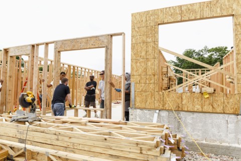 Volunteers holding framed wall at construction site