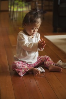 Mixed race baby with Down syndrome playing on floor