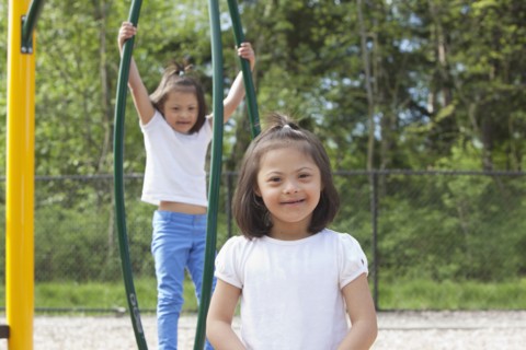 Mixed race Down syndrome girls smiling on playground
