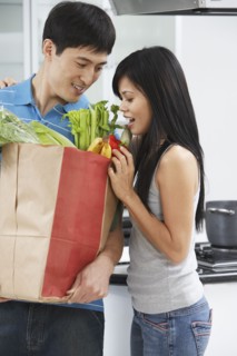 Asian couple looking in grocery bag in kitchen