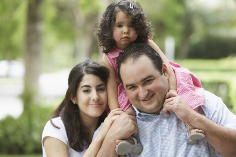 Hispanic father and mother with daughter on shoulders