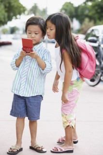 Asian brother and sister playing with handheld game