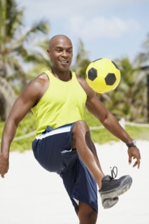 African American man bouncing soccer ball on knee